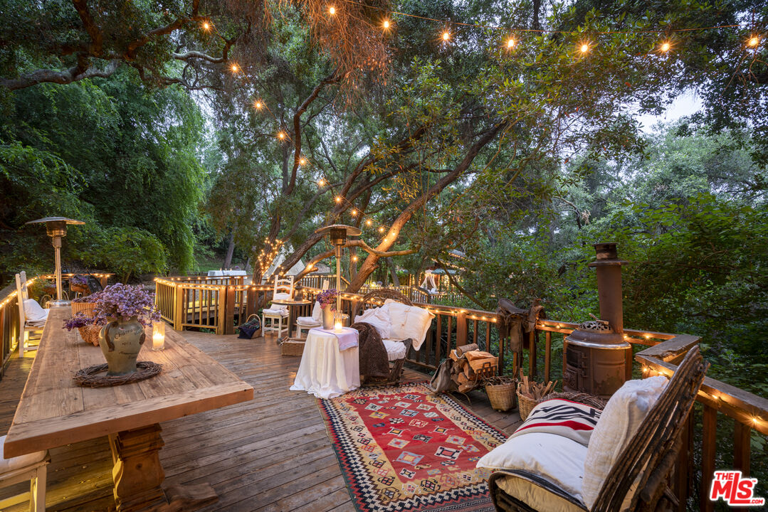 21658 Encina Road Topanga, CA 90290 - Photo 46 of 53 a view of a patio with couches table and chairs with wooden floor and fence