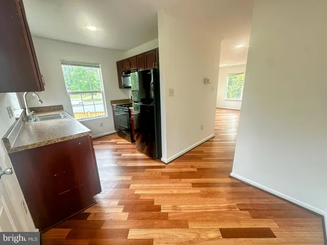 a view of an empty room with wooden floor and windows