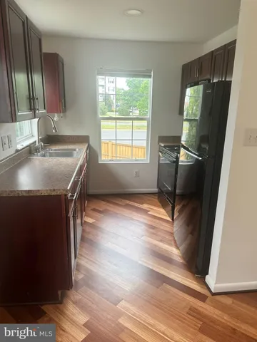 a view of an empty room with wooden floor and windows