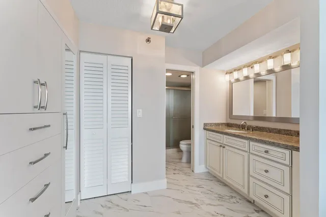 a bathroom with a granite countertop sink a toilet a mirror and vanity