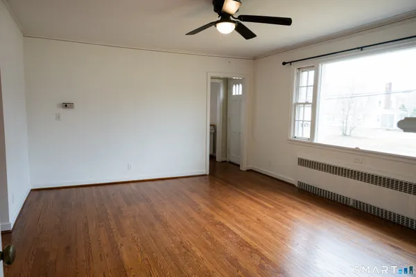 a view of an empty room with wooden floor and a window