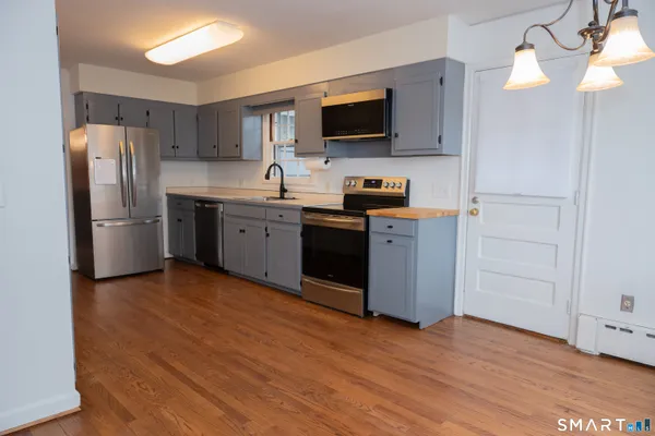 a kitchen with a refrigerator stove and wooden floor
