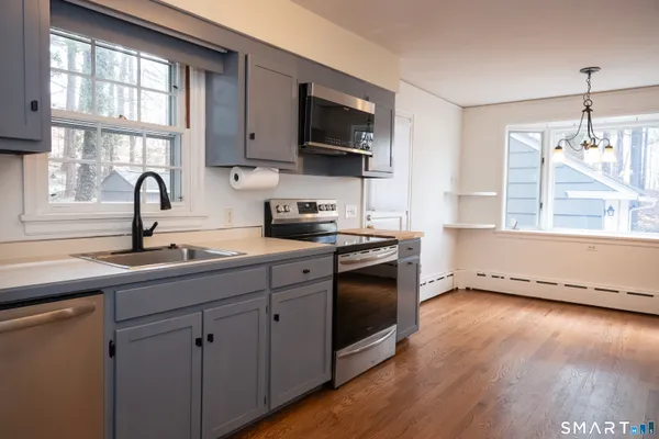 a kitchen with stainless steel appliances granite countertop a sink a stove a refrigerator and a window