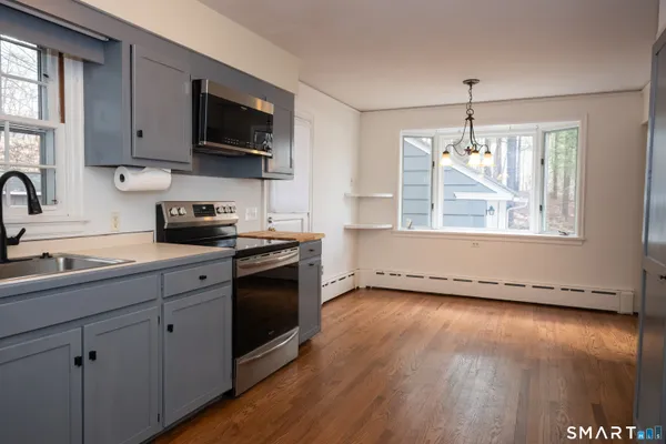 a kitchen with stainless steel appliances granite countertop a sink a stove a microwave a refrigerator a window and cabinets