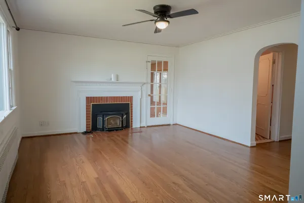 a view of an empty room with wooden floor fireplace and a window