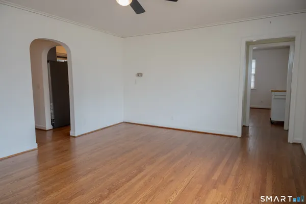 an empty room with wooden floor and a ceiling fan