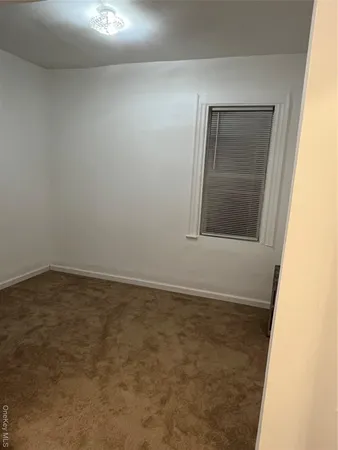 a view of an empty room with closet and mirror