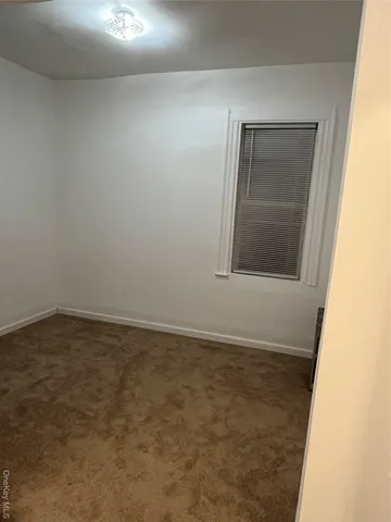 a view of an empty room with closet and mirror