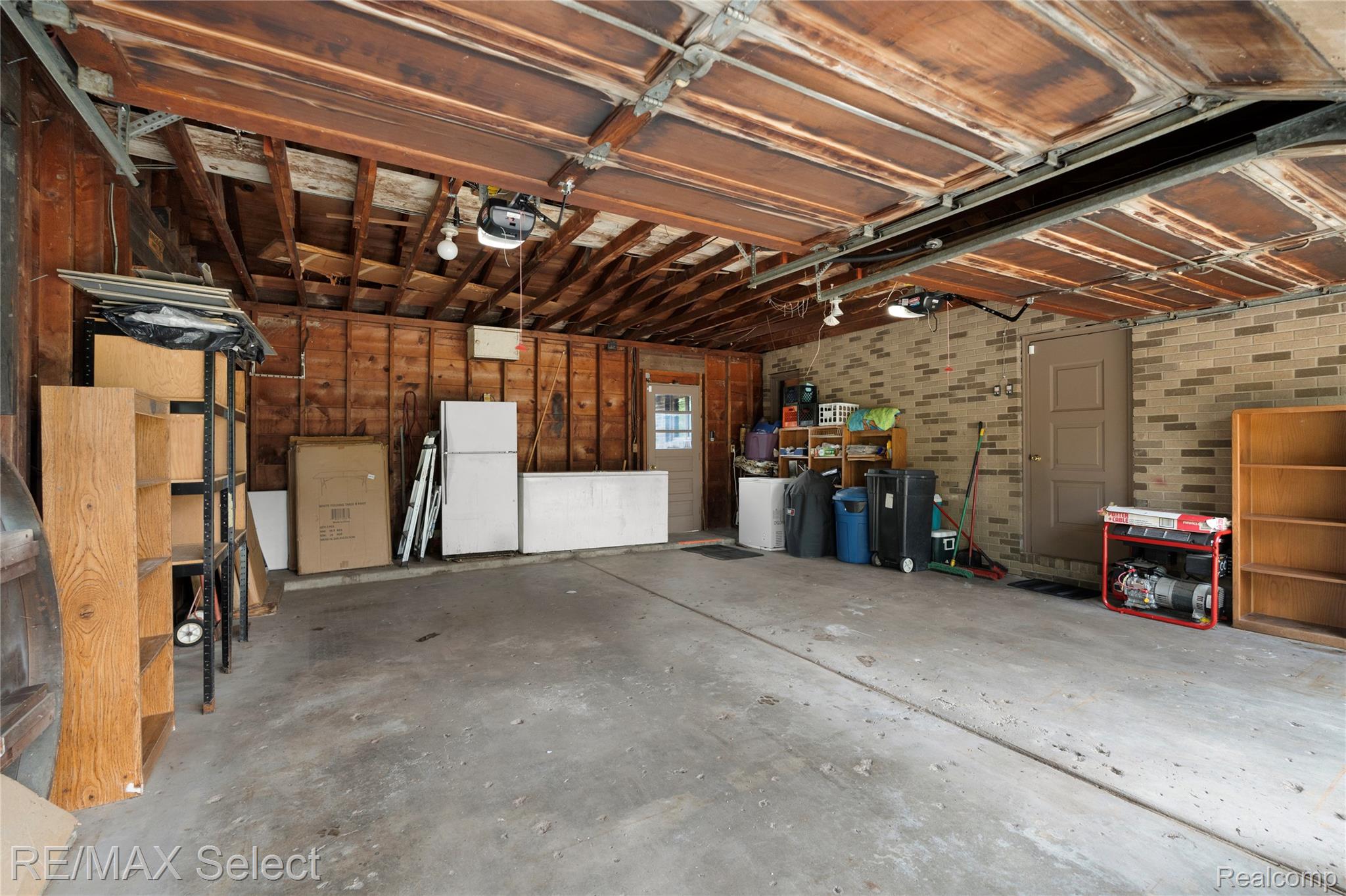 11080 Lapeer Road Davison, MI 48423 - Photo 57 of 64 Concrete flooring with exposed wood beam ceiling, featuring a brick wall and two permanent doors