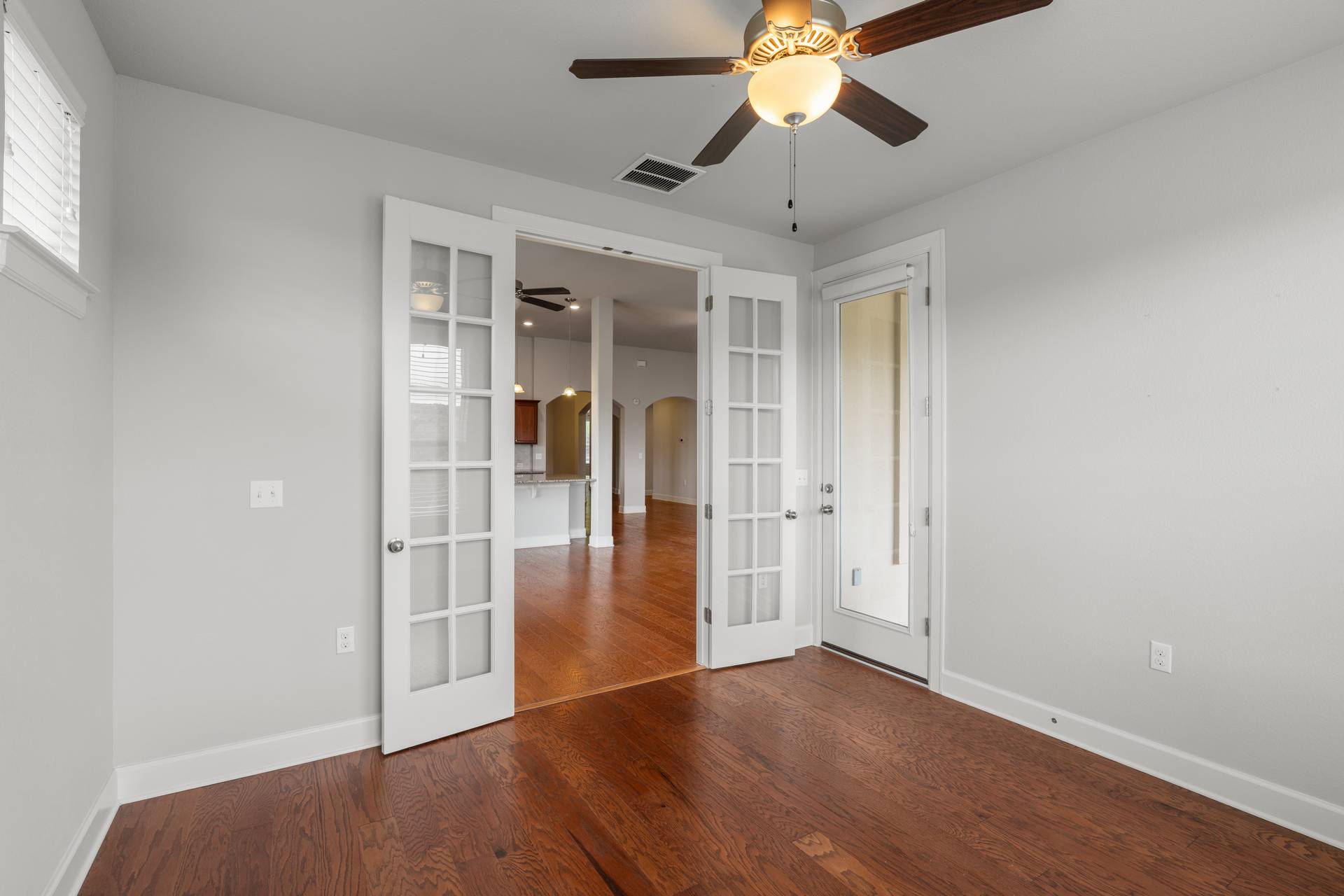 3516 Venezia View Leander, TX 78641 - Photo 29 of 40 Unfurnished bedroom with french doors, arched walkways, ceiling fan, and dark wood-style flooring