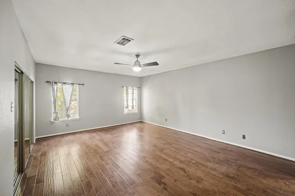 an empty room with wooden floor and windows