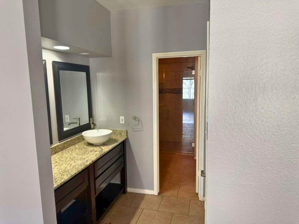 3780 Tanglewilde Street, Unit 306 Houston, TX 77063 - Photo 17 of 22 a bathroom with a granite countertop sink and a mirror