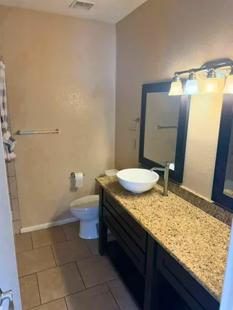 a bathroom with a granite countertop sink and a toilet