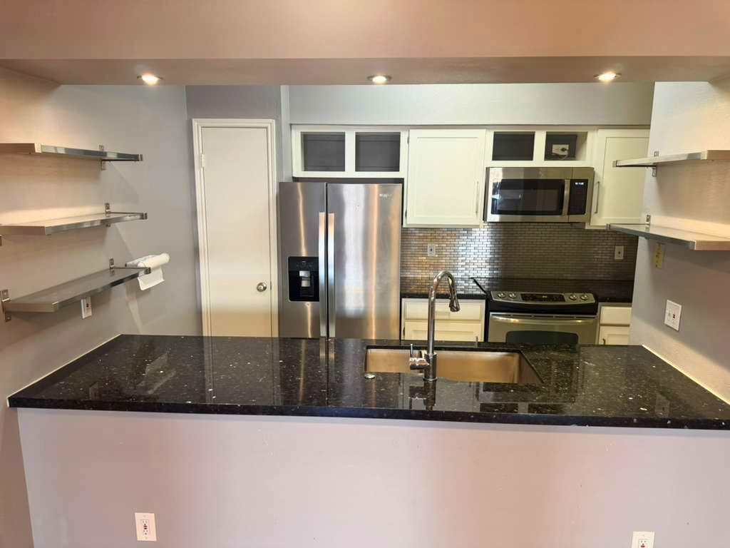 3780 Tanglewilde Street, Unit 306 Houston, TX 77063 - Photo 8 of 22 a kitchen with stainless steel appliances granite countertop a refrigerator a stove and a sink with wooden cabinets