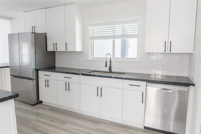 a kitchen with granite countertop white cabinets white appliances a sink and a window