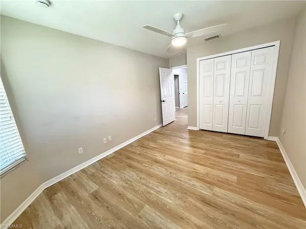 an empty room with a windows and a ceiling fan
