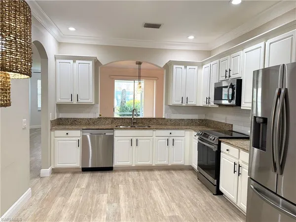a large kitchen with stainless steel appliances granite countertop a stove a sink dishwasher a refrigerator and a oven with wooden floor