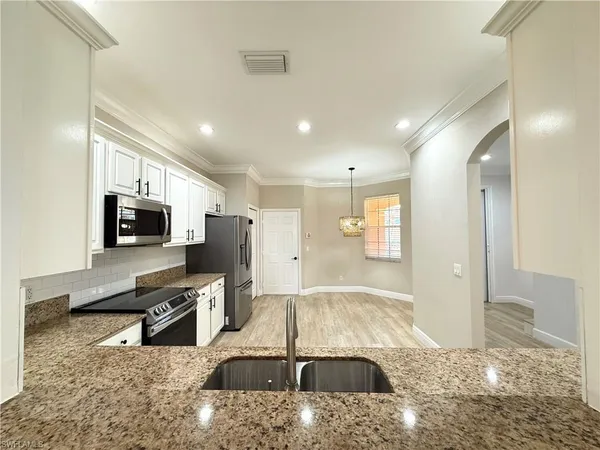 a living room with stainless steel appliances furniture a rug and a view of kitchen