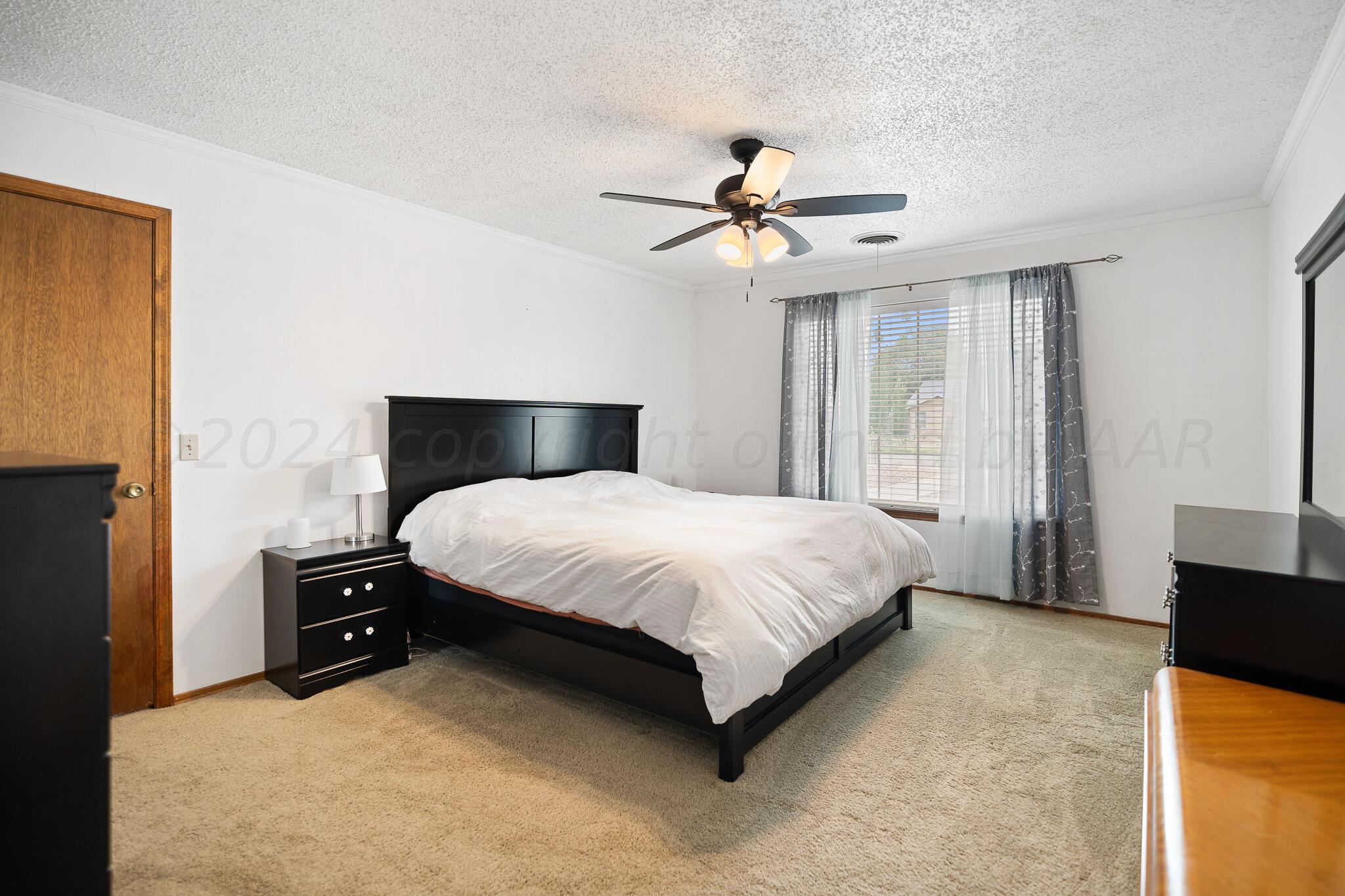 4202 Charles Street Amarillo, TX 79106 - Photo 14 of 25 a bedroom with a large bed and a chandelier