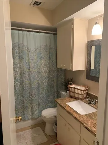 a bathroom with a granite countertop sink a toilet and a mirror