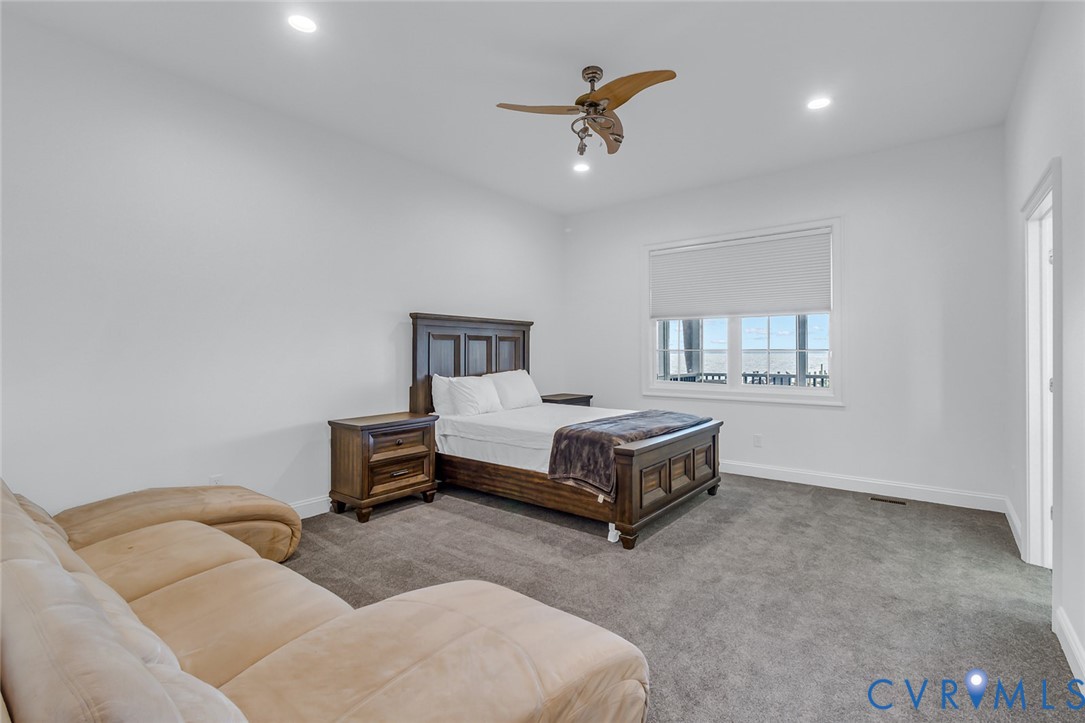 3315 Windmill Point Road White Stone, VA 22578 - Photo 24 of 49 a spacious bedroom with a bed a chandelier and a dresser