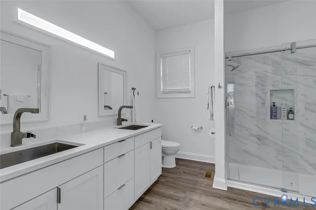 a bathroom with a double vanity sink toilet and shower