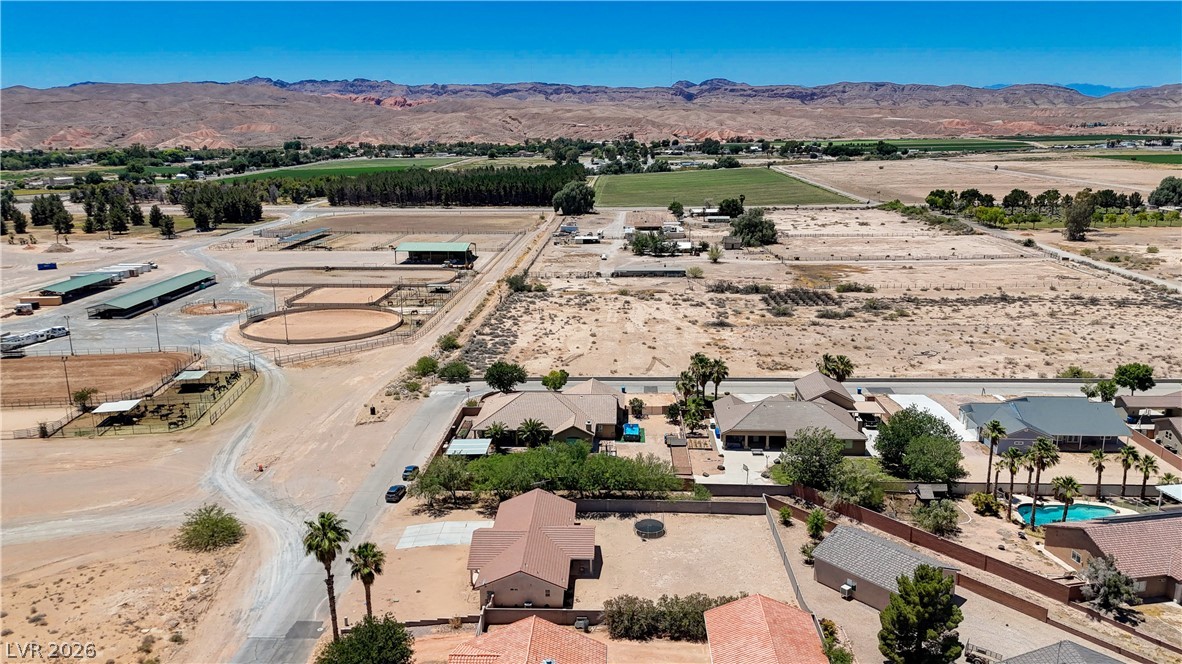 1272 Liston Avenue Logandale, NV 89021 - Photo 58 of 61 An aerial perspective reveals a vast equestrian facility adjacent to residential homes and agricultural land, all framed by distant mountains.