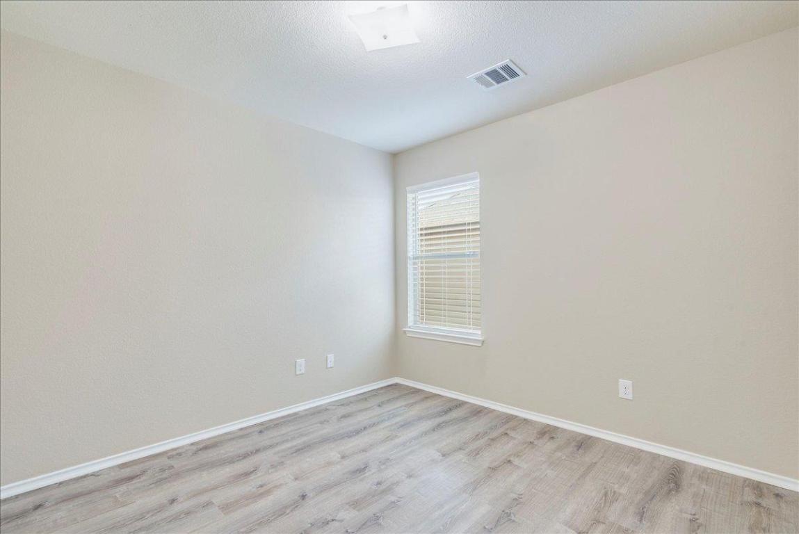 185 Housefinch Loop Leander, TX 78641 - Photo 24 of 39 a view of an empty room with wooden floor and a window