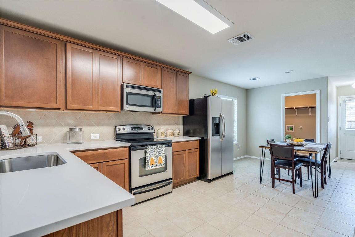 185 Housefinch Loop Leander, TX 78641 - Photo 10 of 39 a kitchen with granite countertop stainless steel appliances a stove top oven a sink a dining table and chairs