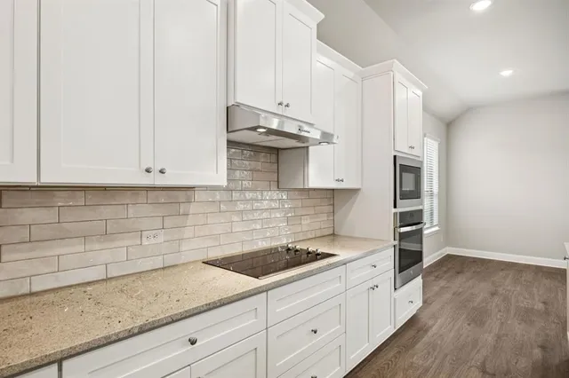 a kitchen with granite countertop white cabinets and white appliances