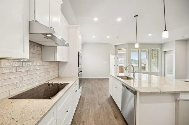 a large kitchen with kitchen island a stove a sink a center island and wooden floor