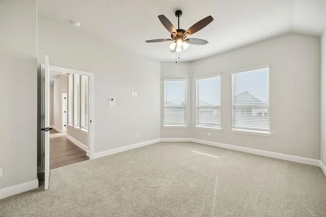 an empty room with windows and chandelier fan
