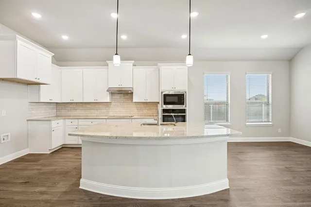 a kitchen with kitchen island a counter top a stove a sink and a wooden floor