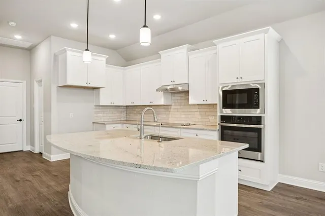 a kitchen with stainless steel appliances granite countertop a sink a stove and a refrigerator