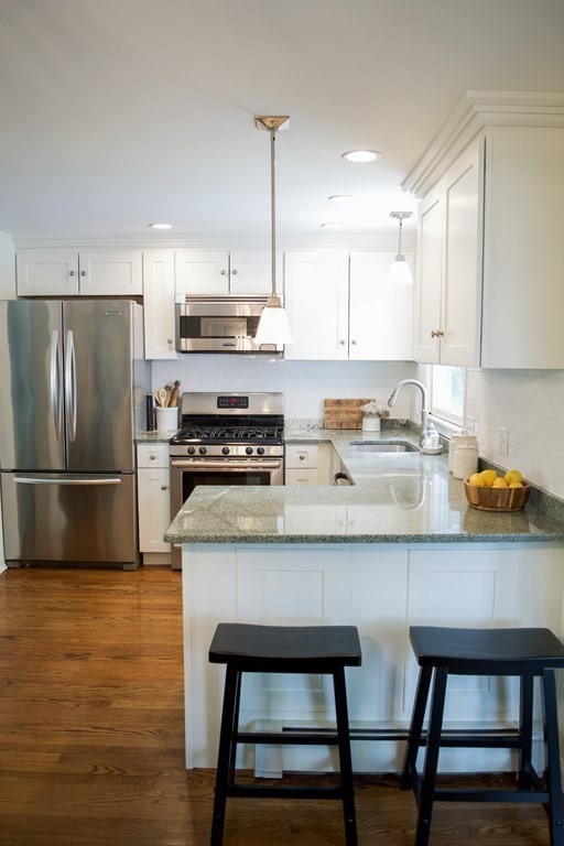 20 Crescent Drive Salem, MA 01970 - Photo 4 of 21 a kitchen with stainless steel appliances granite countertop a stove a sink a refrigerator white cabinets and a chairs