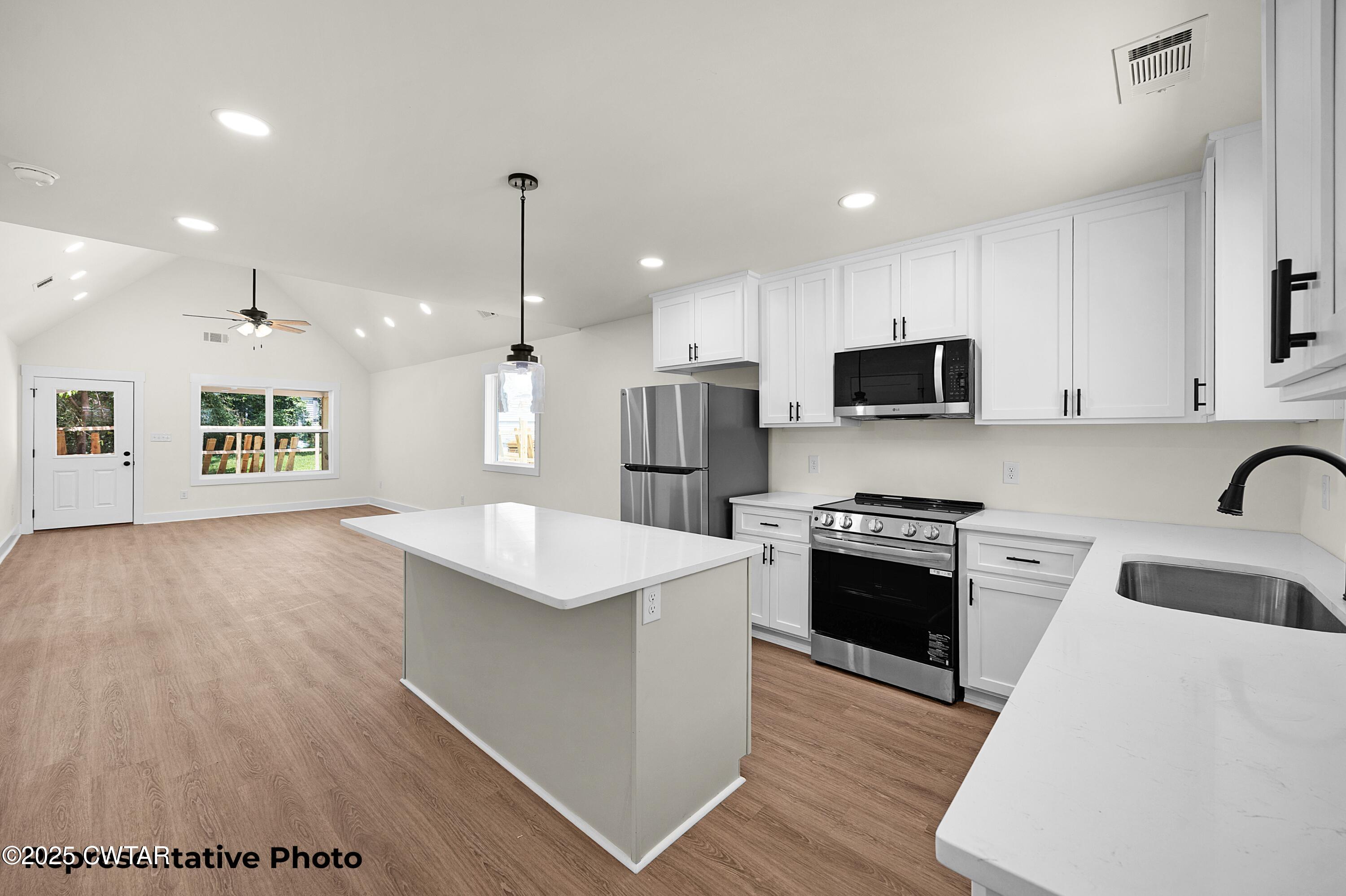 118 Roland Avenue Jackson, TN 38301 - Photo 11 of 24 a kitchen with stainless steel appliances kitchen island granite countertop a stove a sink a refrigerator a microwave oven with white cabinets and wooden floor