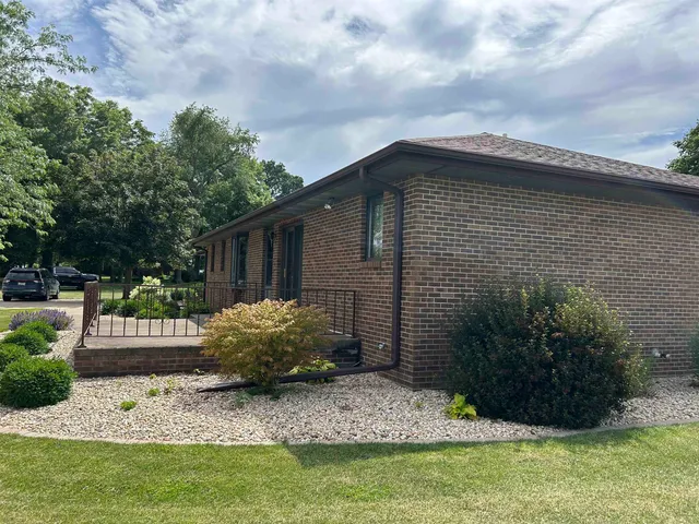 a front view of house with yard and trees in the background