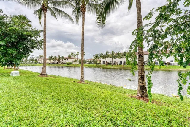 a lake with palm trees next to a house