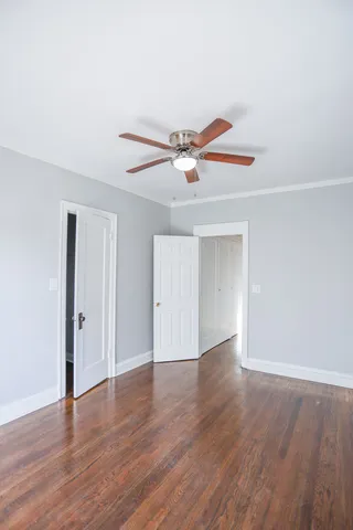 an empty room with wooden floor and a ceiling fan