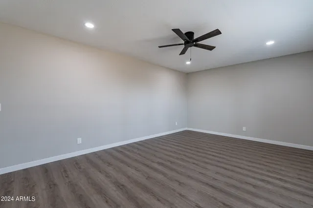an empty room with wooden floor fan and windows