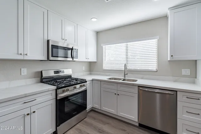 a kitchen with stainless steel appliances a sink a stove a microwave cabinets and a window