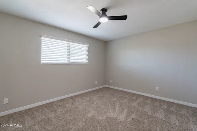 an empty room with a ceiling fan and window