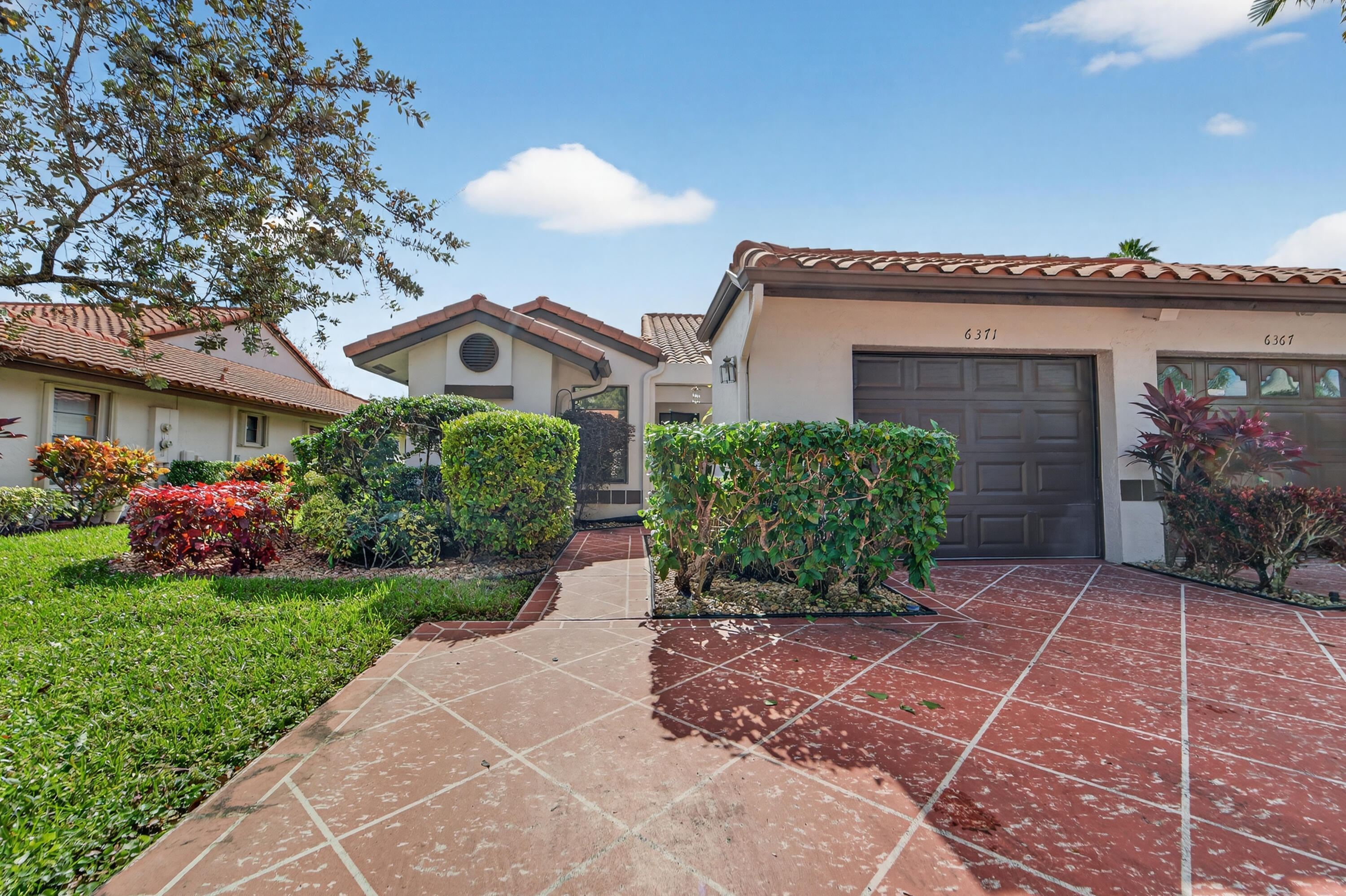 6371 Kings Gate Circle Delray Beach, FL 33484 - Photo 27 of 52 a front view of a house with a garden
