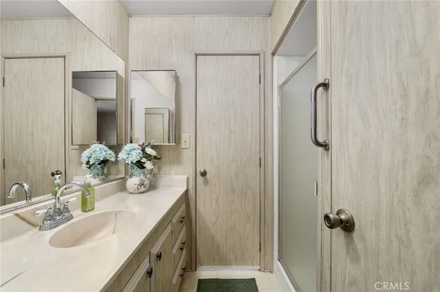 a bathroom with a granite countertop sink vanity mirror and shower