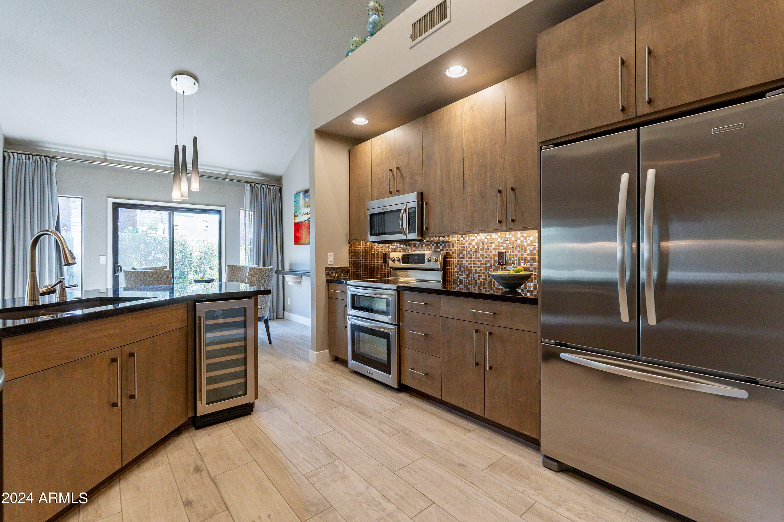 7272 East Gainey Ranch Road, Unit 101 Scottsdale, AZ 85258 - Photo 11 of 36 a kitchen with stainless steel appliances granite countertop a refrigerator a sink dishwasher a stove and white countertops with wooden floor