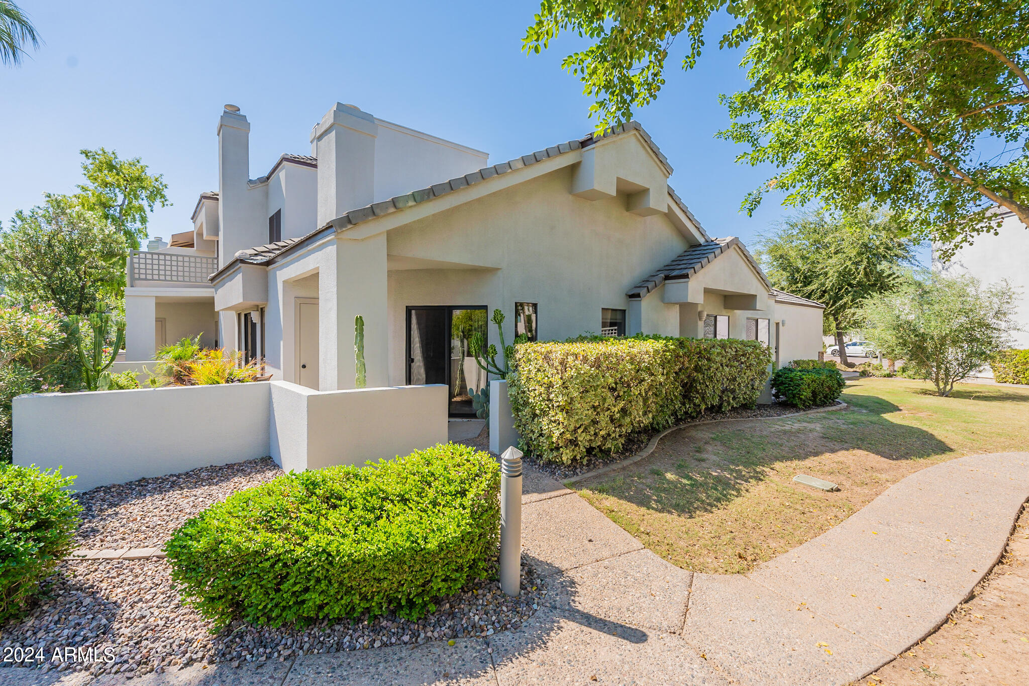 7272 East Gainey Ranch Road, Unit 101 Scottsdale, AZ 85258 - Photo 30 of 36 a view of a house with a yard and potted plants