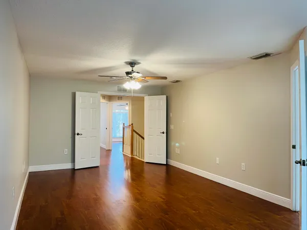 a view of an empty room with wooden floor and a window