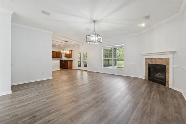 an empty room with wooden floor fireplace and windows