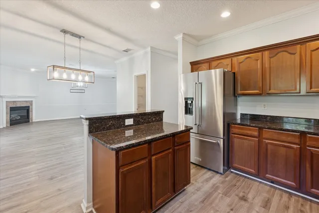 a kitchen with stainless steel appliances granite countertop a refrigerator a sink dishwasher a stove with wooden cabinets and floor