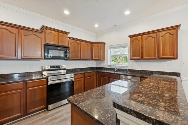 a kitchen with stainless steel appliances granite countertop a stove a sink and a microwave